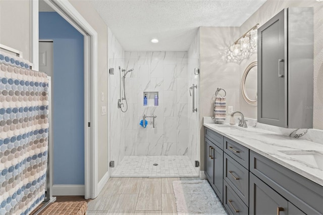 bathroom with a textured ceiling, vanity, and a shower with door