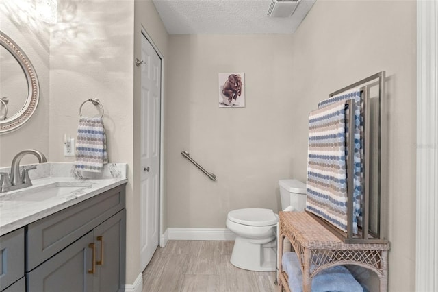 bathroom featuring vanity, a textured ceiling, and toilet