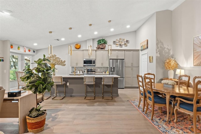 dining space featuring a textured ceiling, light hardwood / wood-style floors, and lofted ceiling