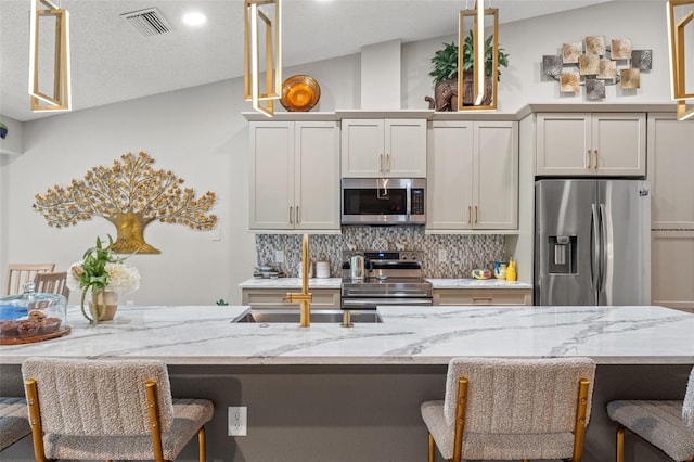 kitchen featuring a breakfast bar area, decorative backsplash, stainless steel appliances, and vaulted ceiling