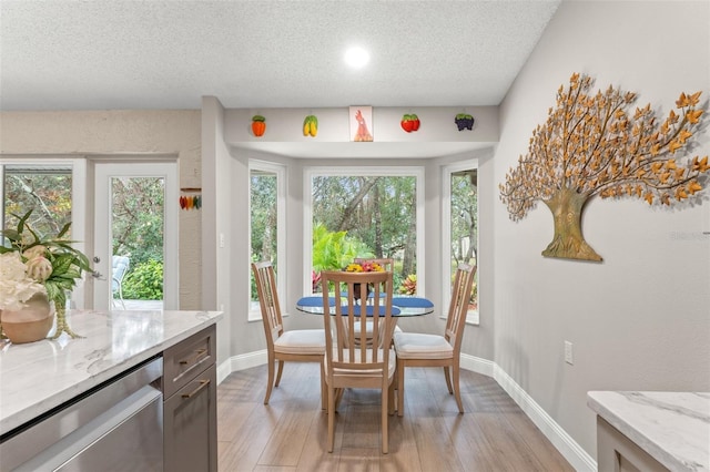 dining space with light hardwood / wood-style flooring and a textured ceiling