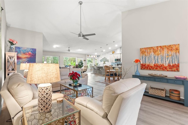 living room featuring ceiling fan, light hardwood / wood-style floors, and vaulted ceiling