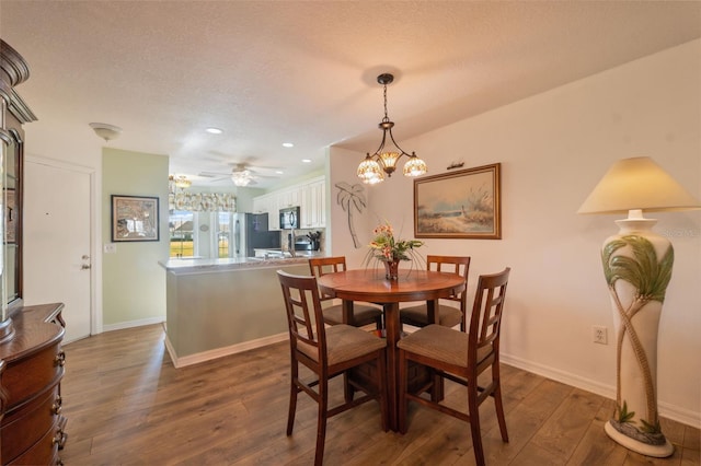 dining room featuring a textured ceiling, dark hardwood / wood-style floors, and ceiling fan with notable chandelier