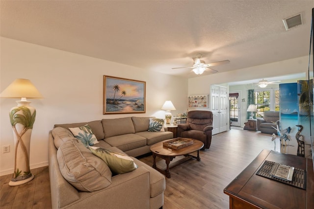 living room with hardwood / wood-style flooring, a textured ceiling, and ceiling fan