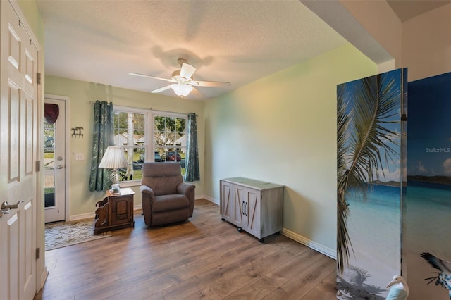 living area featuring hardwood / wood-style flooring, a textured ceiling, and ceiling fan