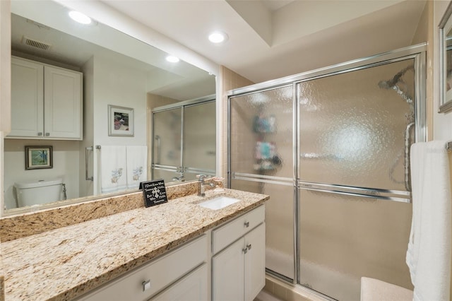 bathroom featuring toilet, an enclosed shower, and vanity