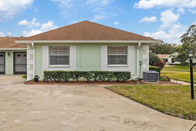 view of front of home featuring central air condition unit, a front yard, and a garage