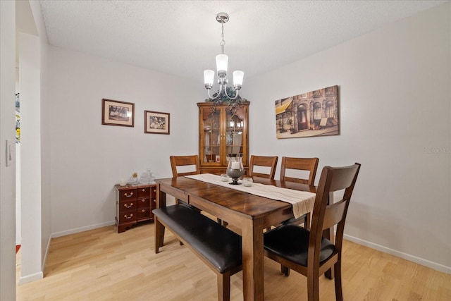 dining space featuring a textured ceiling, a chandelier, and light wood-type flooring