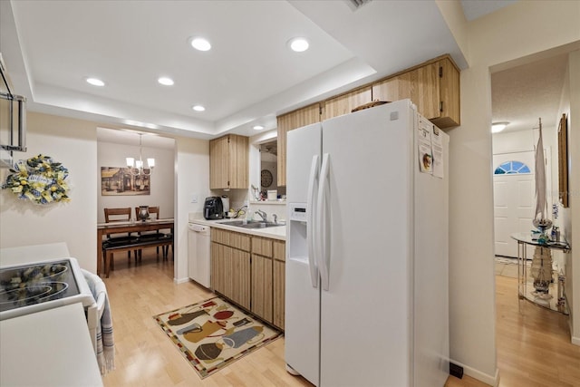 kitchen featuring white appliances, light wood-type flooring, a raised ceiling, and sink