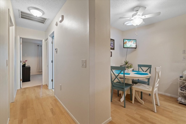 hall with a textured ceiling and light wood-type flooring