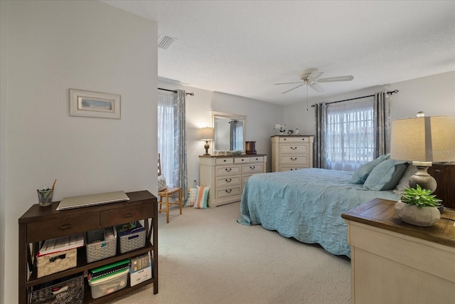 bedroom with a textured ceiling, ceiling fan, and light carpet