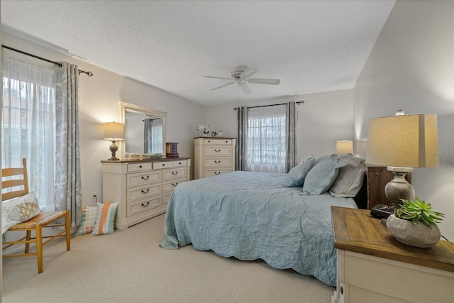 bedroom with ceiling fan, light carpet, multiple windows, and a textured ceiling