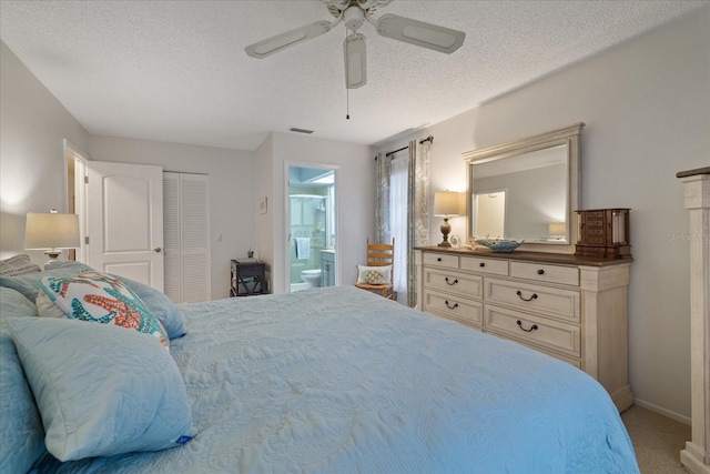 bedroom with a textured ceiling, carpet, ceiling fan, a closet, and ensuite bath