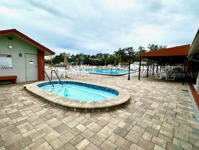 view of swimming pool with a community hot tub and a patio