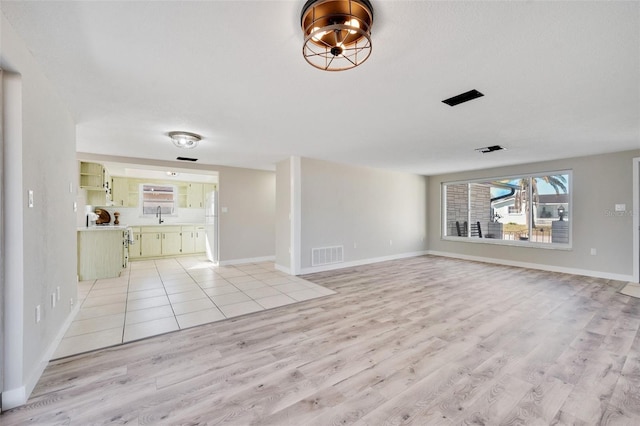 unfurnished living room with light hardwood / wood-style floors and sink