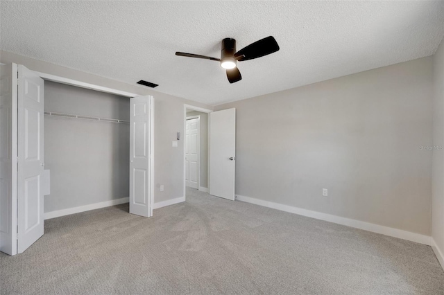 unfurnished bedroom featuring a closet, light carpet, ceiling fan, and a textured ceiling