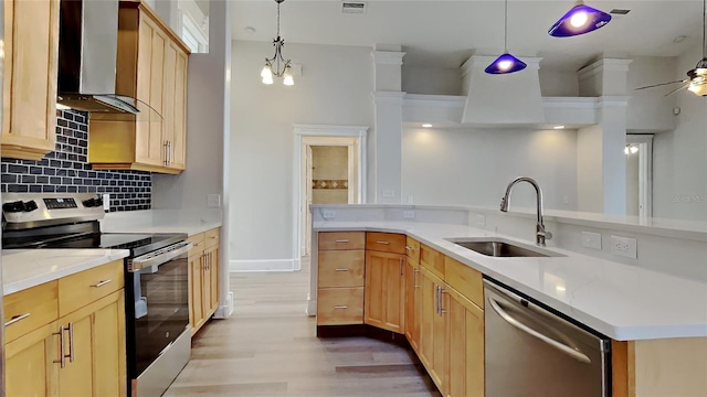 kitchen featuring pendant lighting, sink, wall chimney range hood, and stainless steel appliances