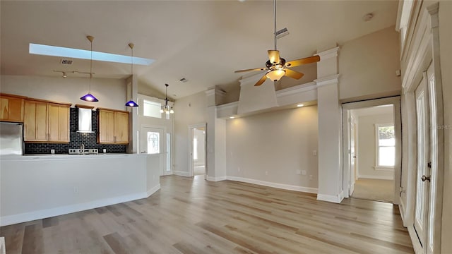 kitchen featuring stainless steel refrigerator, light hardwood / wood-style flooring, high vaulted ceiling, decorative backsplash, and ceiling fan with notable chandelier