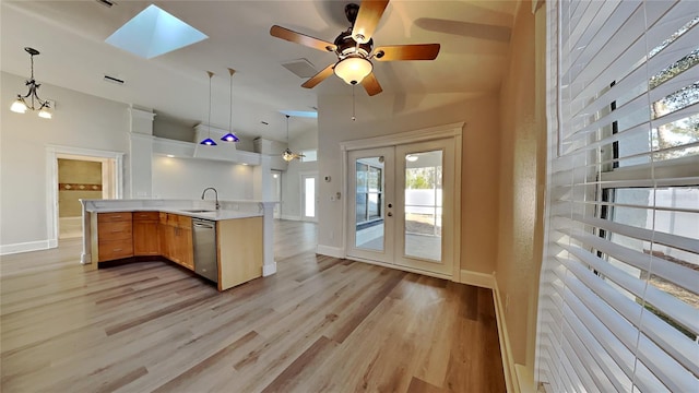 kitchen with pendant lighting, lofted ceiling with skylight, french doors, and stainless steel dishwasher