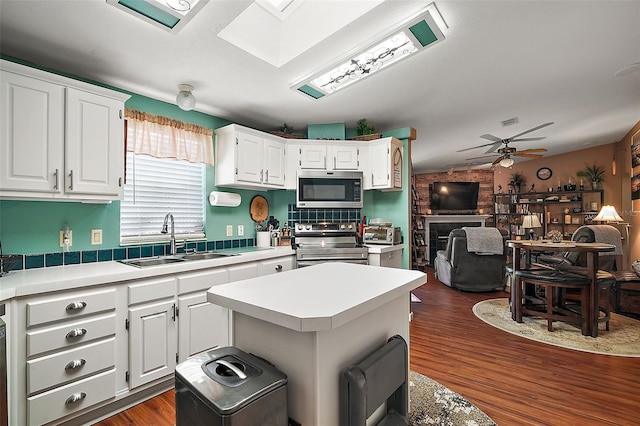 kitchen featuring sink, ceiling fan, a kitchen island, white cabinetry, and stainless steel appliances