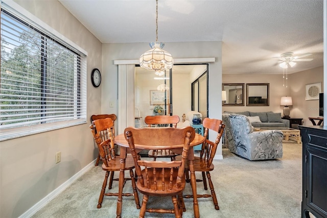 dining room featuring ceiling fan with notable chandelier, carpet floors, and a textured ceiling