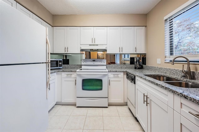 kitchen with light stone counters, a textured ceiling, white appliances, sink, and white cabinetry