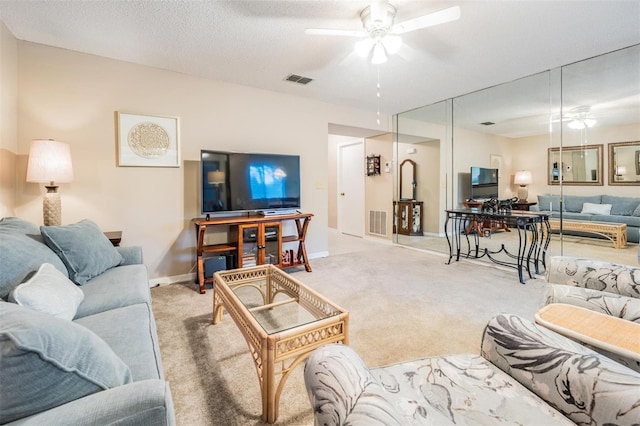 living room with ceiling fan, light colored carpet, and a textured ceiling