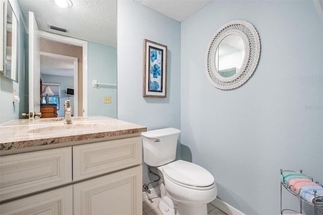 bathroom featuring vanity, toilet, and a textured ceiling