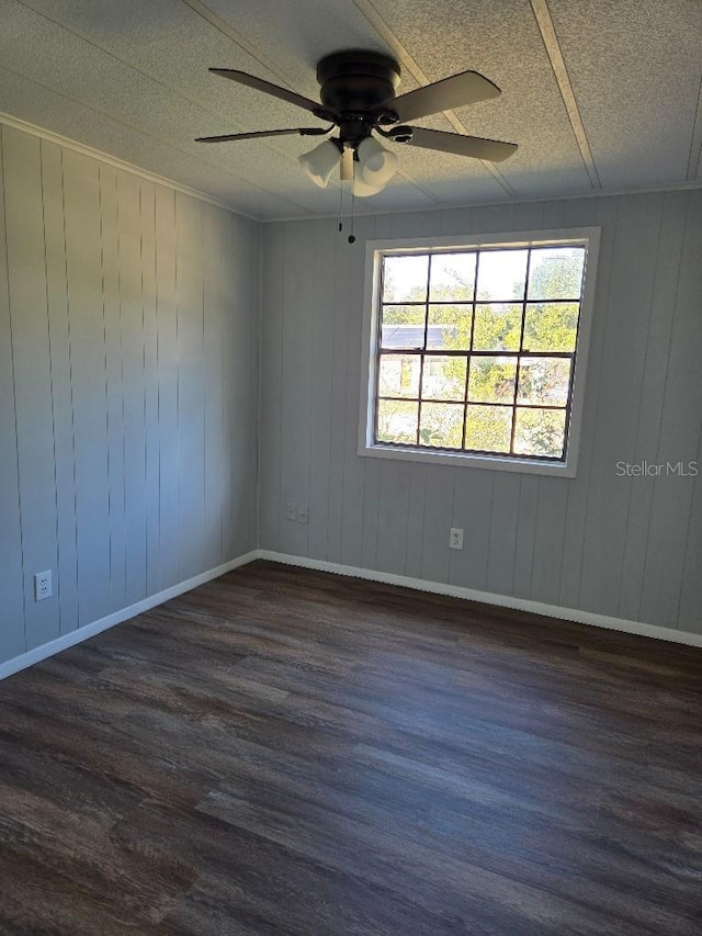 spare room with ceiling fan, dark hardwood / wood-style flooring, and wooden walls