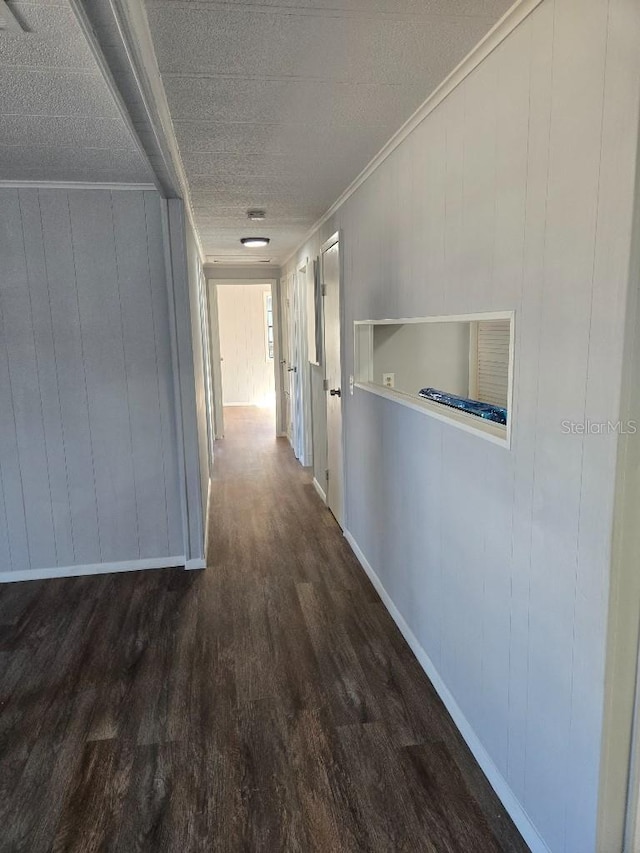 hallway featuring dark hardwood / wood-style flooring, ornamental molding, and a textured ceiling