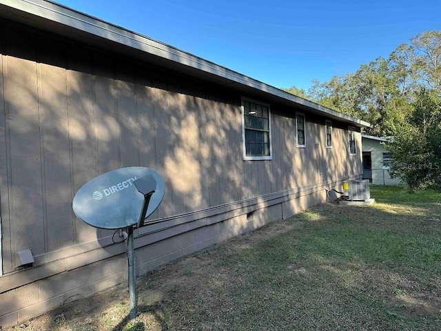 view of side of home featuring cooling unit and a yard