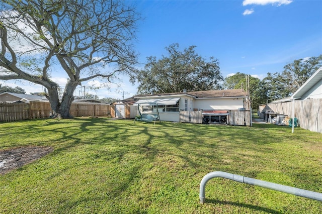 view of yard featuring an outbuilding, a fenced backyard, and a shed