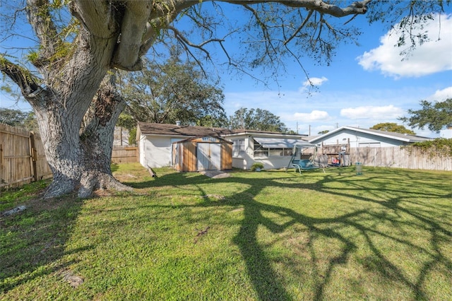 view of yard featuring a fenced backyard, an outbuilding, and a storage unit