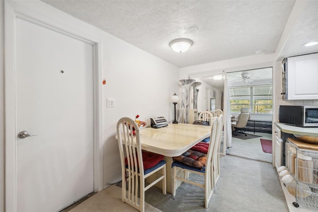 dining room with light colored carpet and a textured ceiling
