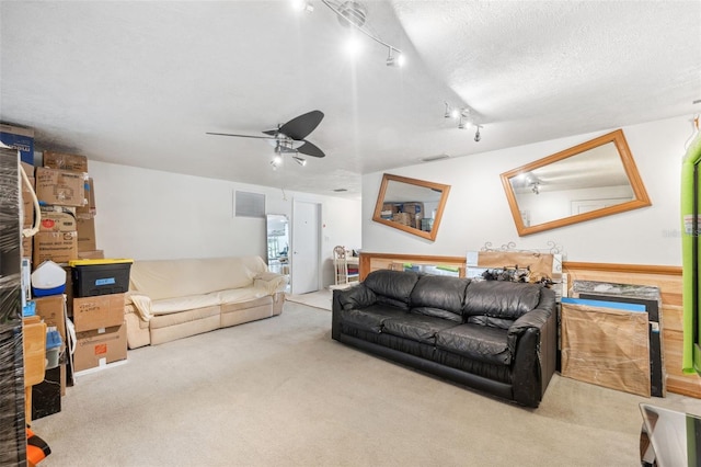 living area with a ceiling fan, visible vents, carpet, and a textured ceiling