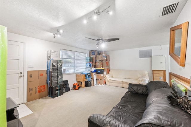 living room featuring carpet flooring, a textured ceiling, visible vents, and a ceiling fan
