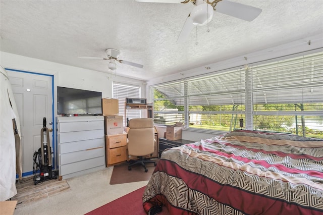 bedroom with a ceiling fan, carpet, and a textured ceiling