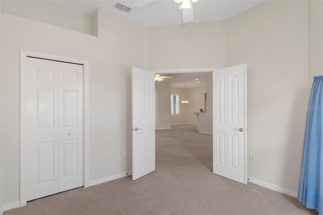 unfurnished bedroom featuring ceiling fan, light colored carpet, and a closet