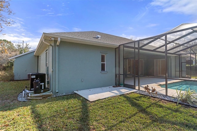 back of house with central air condition unit, a lanai, a patio area, and a yard