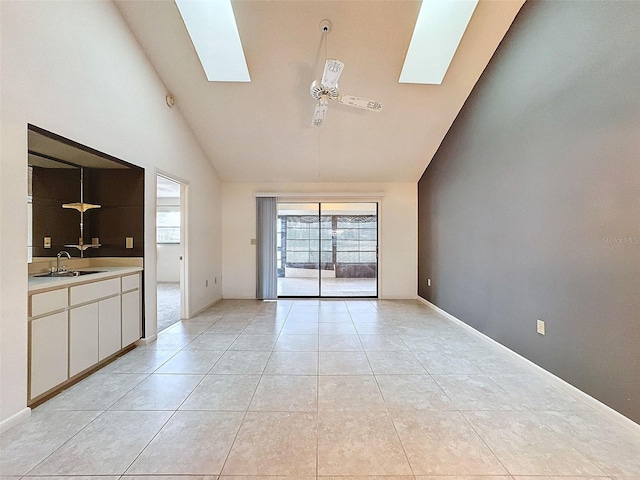 unfurnished living room with sink, high vaulted ceiling, a skylight, and ceiling fan