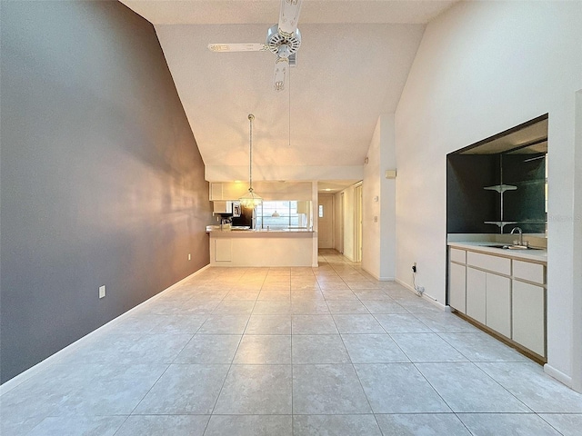 unfurnished living room with high vaulted ceiling, ceiling fan, light tile patterned floors, and sink