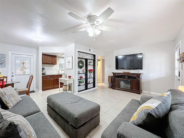 living room featuring ceiling fan, a textured ceiling, and light tile patterned floors