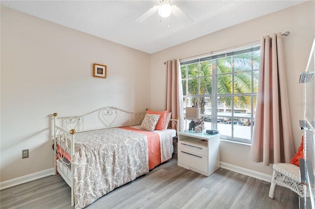 bedroom featuring hardwood / wood-style floors, ceiling fan, a textured ceiling, and multiple windows