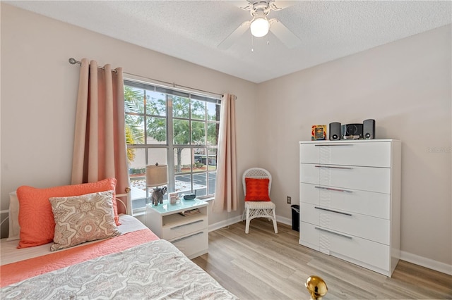 bedroom with a textured ceiling, light hardwood / wood-style flooring, and ceiling fan