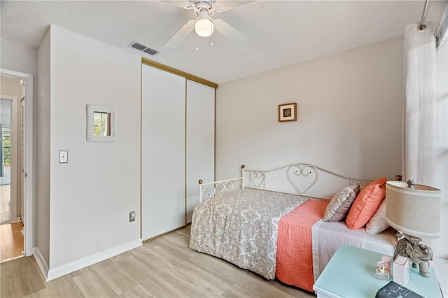 bedroom featuring a textured ceiling, light wood-type flooring, a closet, and ceiling fan