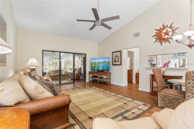 living room with hardwood / wood-style flooring, ceiling fan with notable chandelier, and high vaulted ceiling