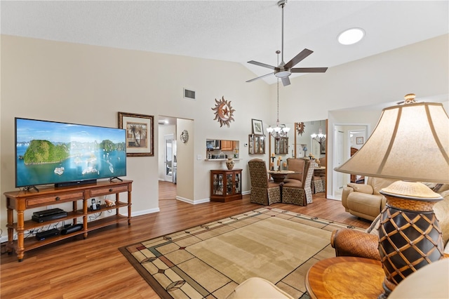 living room featuring hardwood / wood-style floors, ceiling fan with notable chandelier, and high vaulted ceiling