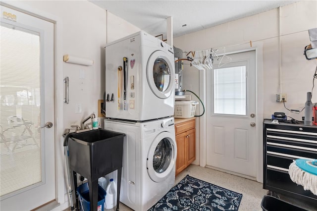 washroom featuring cabinets, stacked washing maching and dryer, and sink