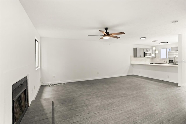 unfurnished living room featuring ceiling fan and dark hardwood / wood-style flooring