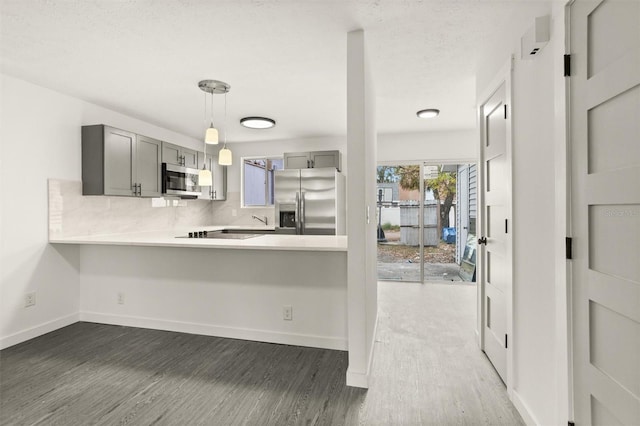 kitchen featuring gray cabinetry, kitchen peninsula, appliances with stainless steel finishes, and tasteful backsplash